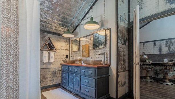 A rustic bathroom with a wooden vanity, two pendant lights, and a large mirror.