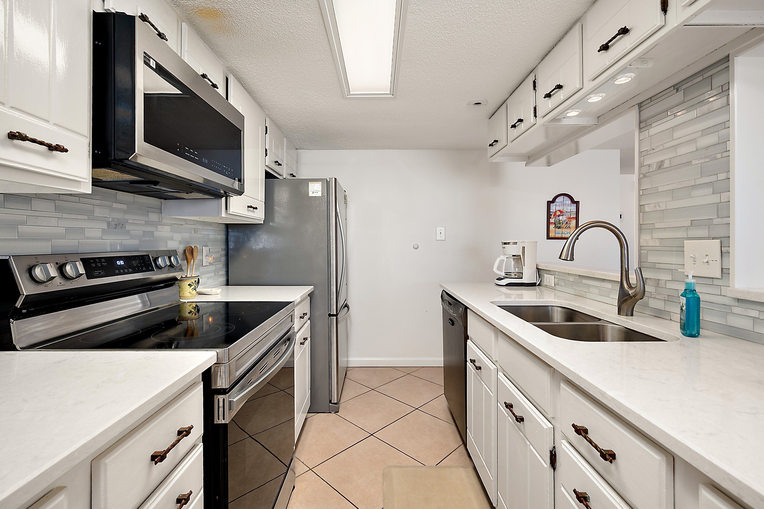 Una cocina moderna con armarios blancos, electrodomésticos de acero inoxidable y un salpicadero de azulejos.