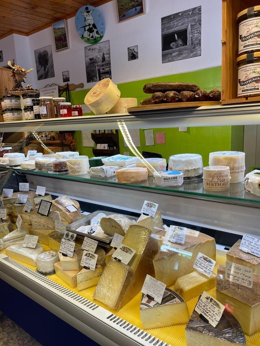 A cheese display in a store with various types of cheese on shelves and in a case.