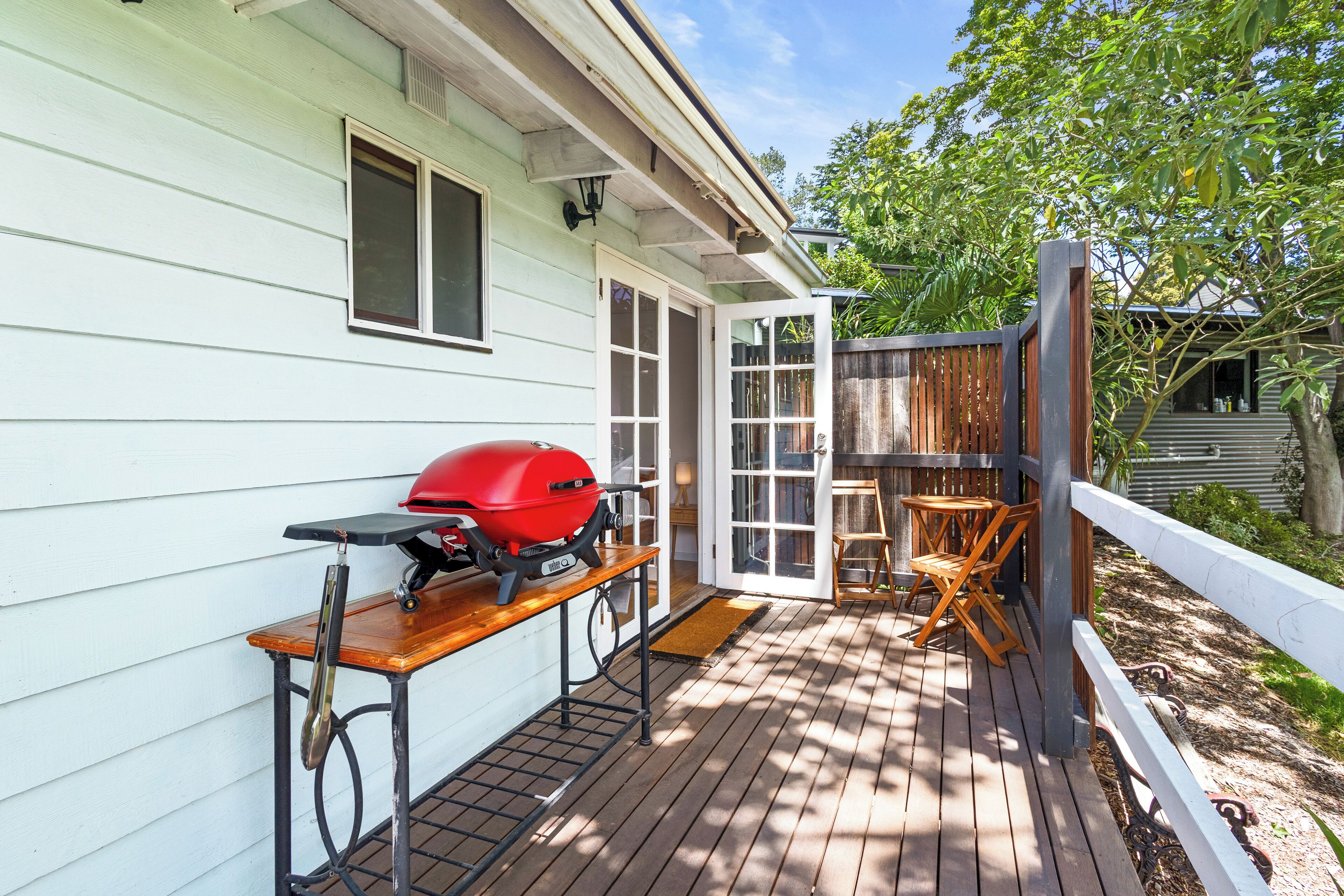 A wooden deck with a barbecue grill, a table, and chairs.