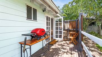 A wooden deck with a barbecue grill, a table, and chairs.