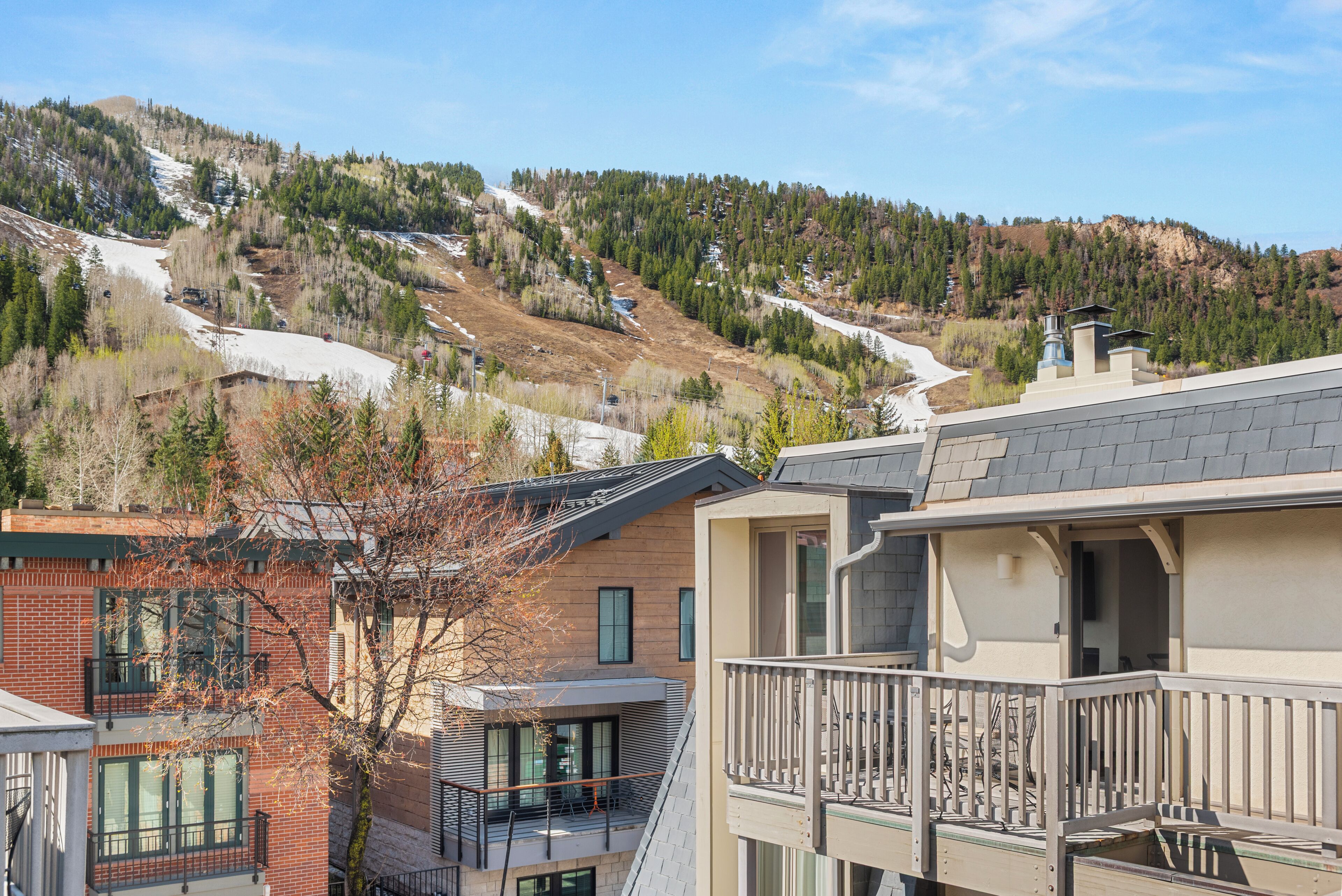 Zona residencial con montañas al fondo, con edificios modernos que tienen balcones y una pista de esquí.