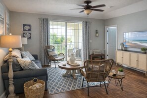 A spacious living room with a sofa, chairs, a coffee table, and a television. - Barefoot Bungalow- 5 minutes from the beach, shops, music and restaurants! (North Myrtle Beach)