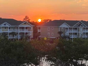A beachfront hotel with multiple-story buildings, balconies, and a sunset view. - Barefoot Bungalow- 5 minutes from the beach, shops, music and restaurants! (North Myrtle Beach)
