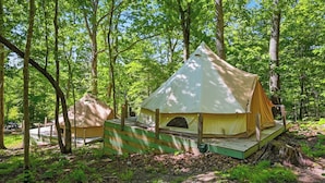 A tented campsite with a platform, surrounded by trees. - Glamping Tent in Red River Gorge w/ Heater and Hot Tub (Stanton)