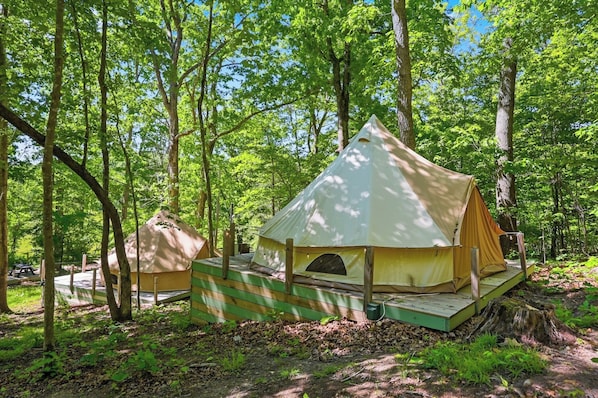 A tented campsite with a platform, surrounded by trees.