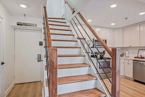 Un escalier avec des marches en bois et des rampes en métal menant à un espace cuisine.