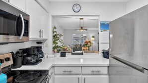 A modern kitchen with white cabinets, stainless steel appliances, and a central island.