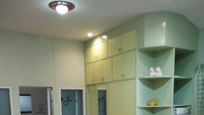Quarto com duas camas, um guarda-roupa e uma pequena cozinha compacta.