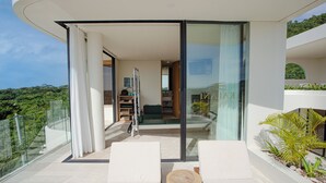 A modern balcony with glass doors, white furniture, and a view of greenery. - Villa Kalani Spirit by Alfred in Bali (Pecatu)