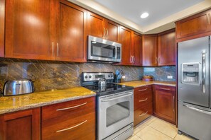 A kitchen with wooden cabinets, a stainless steel refrigerator, a microwave, a stove, and a toaster. - 2 Kapalua Ridge Villas | Ocean View | Sleeps 8 | Free Car w/ 6+ Nights | ML-3535 (Lahaina)