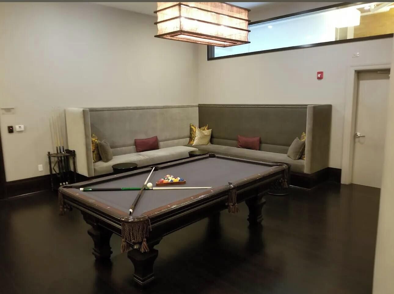 A pool table in a room with a sofa and a ceiling light fixture.