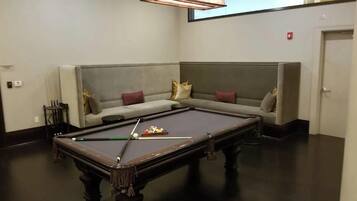 A pool table in a room with a sofa and a ceiling light fixture.