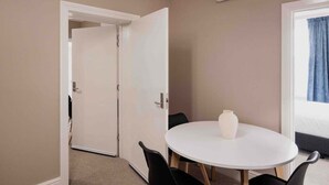 Ett hotellrum med ett runt bord, en vas, en säng och en luftkonditioneringsanläggning.