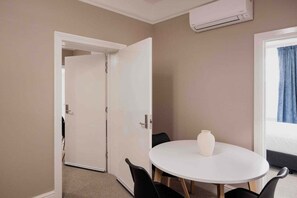 A hotel room with a round table, a vase, a bed, and an air conditioning unit. - Palfreymans Arcade | Central NoHo 2 Bed Apartment - 2 (Hobart City)