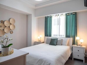 Ein ordentlich eingerichtetes Schlafzimmer mit einem Bett, Nachttischen und einem Beistelltisch mit Lampen.