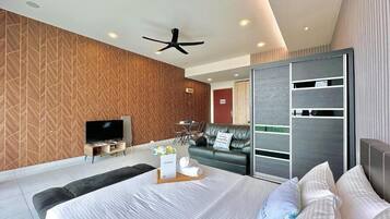 A modern hotel room with a large bed, a TV, a sofa, and a sliding door closet.