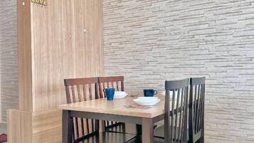 A dining area with a wooden table and chairs, a stone-textured wall, and a wooden cabinet with a 'LOVE' sign.