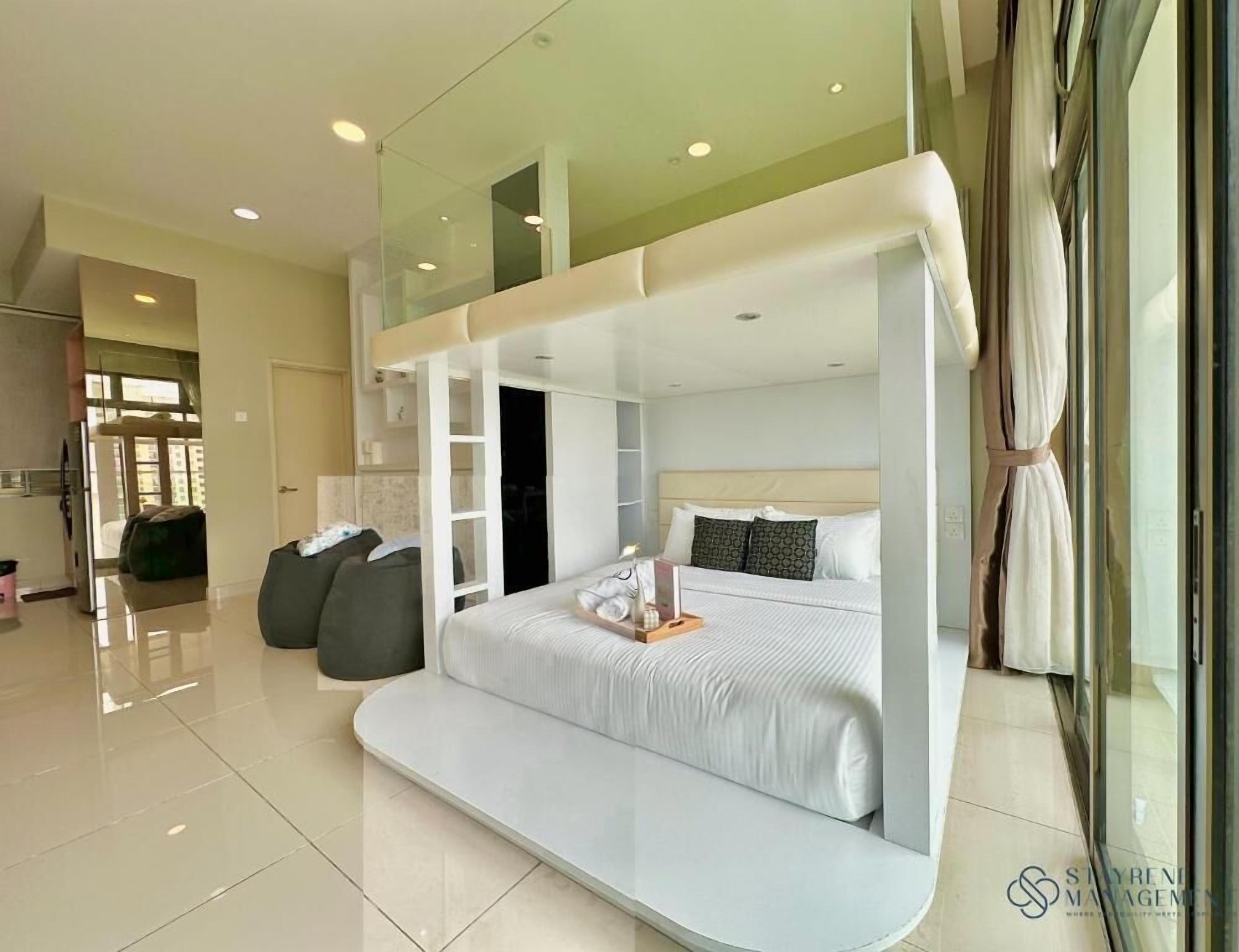 Een moderne hotelkamer met een groot bed, een slaapbank en een glazen scheiding.