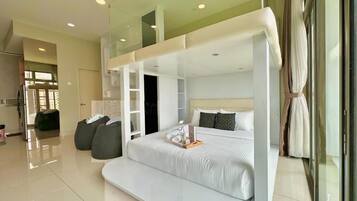 Een moderne hotelkamer met een groot bed, een slaapbank en een glazen scheiding.