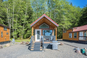 A lodge with a wooden exterior, a porch, a grill, and a number sign.