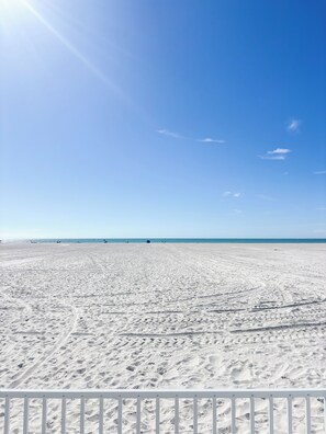 Una extensa playa de arena con cielo despejado y horizonte lejano.