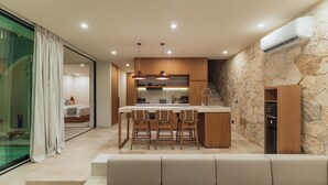 A modern kitchen with a central island, bar stools, and a built-in oven. - Villa Kalani Soul by Alfred in Bali (Pecatu)