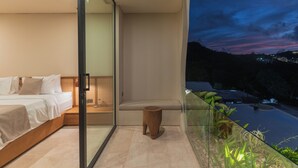 A modern bedroom with a large bed, a small wooden stool, and a glass balcony overlooking a cityscape at dusk. - Villa Kalani Soul by Alfred in Bali (Pecatu)