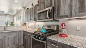 Eine moderne Küche mit dunklen Holzschränken, Edelstahlgeräten, Granitarbeitsplatten und einem roten Standmixer.