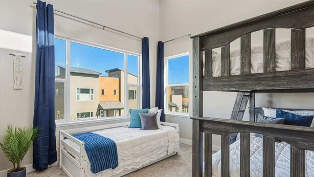 Ein Schlafzimmer mit einem Bett, einem Fenster, Blick auf Gebäude und einem Holzkopfteil.