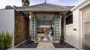 A traditional Japanese-style entrance with a tiled roof, a stone wall, and a tiled pathway leading to a covered seating area. - Villa Luxe Bali 1 (Seminyak)
