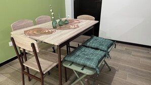 Una mesa de comedor con mantel tejido, tres sillas y un banco con cojín a cuadros.