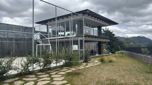 Una casa moderna de dos plantas con balcón, patio cercado y parque infantil.