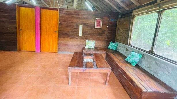 A wooden interior with a bench, a table, and a window with a view of greenery.
