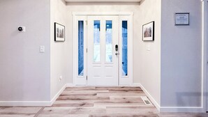 Un corridoio con una porta doppia, una plafoniera e un quadro appeso al muro.