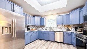 Una cucina moderna con mobili blu, elettrodomestici in acciaio inossidabile e un lucernario.