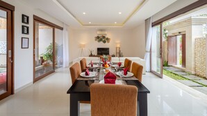 Un comedor con una mesa negra, sillas blancas y una isla central con una planta.