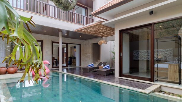 Un área interior de piscina moderna con sillones de descanso y una zona de comedor al fondo.