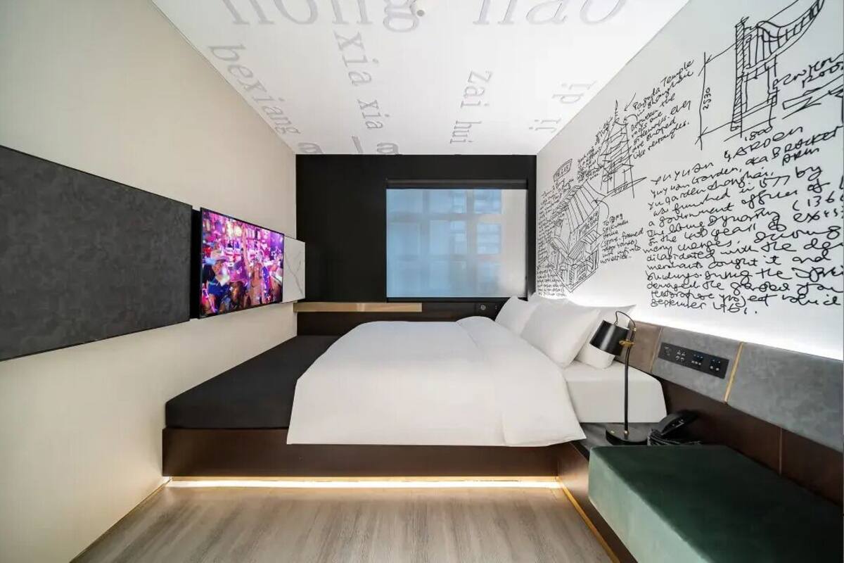 Ein modernes Schlafzimmer mit einem großen Bett, einem Fernseher und einer Wand mit architektonischen Zeichnungen.