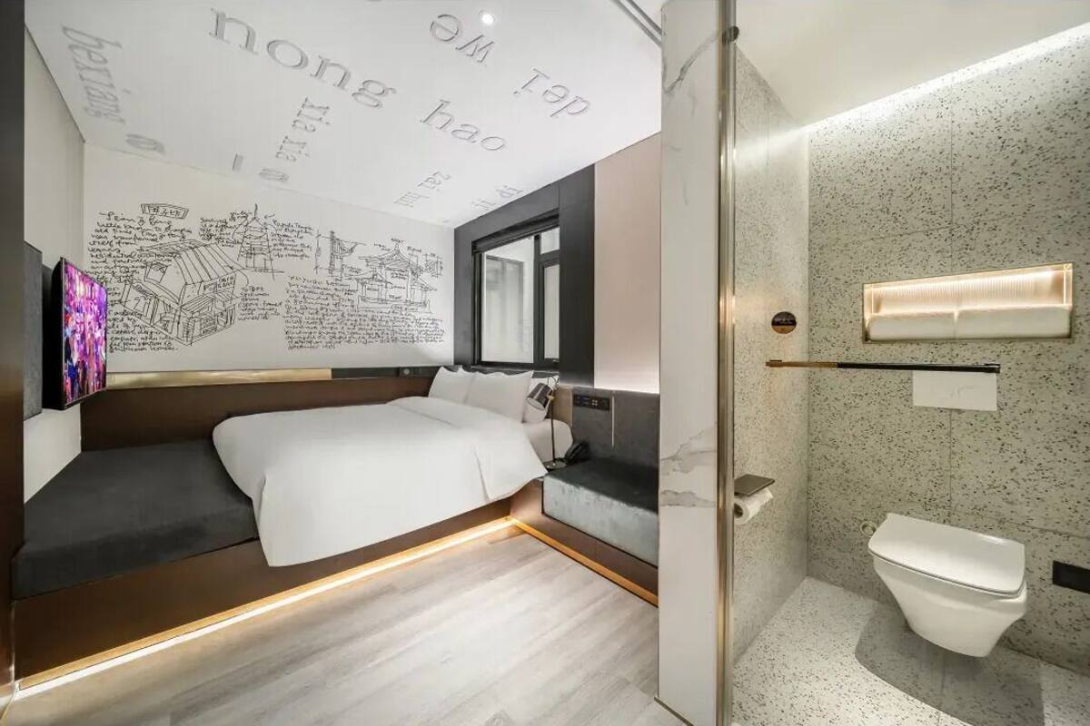 Ein modernes Hotelzimmer mit Bett, Bad und einer Wand mit Text und Zeichnungen.