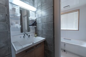 A modern bathroom with a white sink, mirror, and built-in shelves. - Hale Twelve AB (Miyakojima)