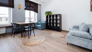 Ein modernes Wohnzimmer mit Essbereich, einer Couch, einem Bücherregal und einer Zimmerpflanze.