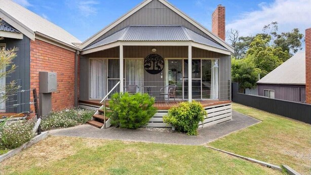 A two-story house with a covered porch, a brick exterior, and a small garden.