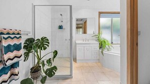 A modern bathroom with a shower, a sink, and a window.