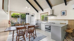 A modern kitchen with a dining area, featuring a large island, built-in appliances, and a view of the garden.