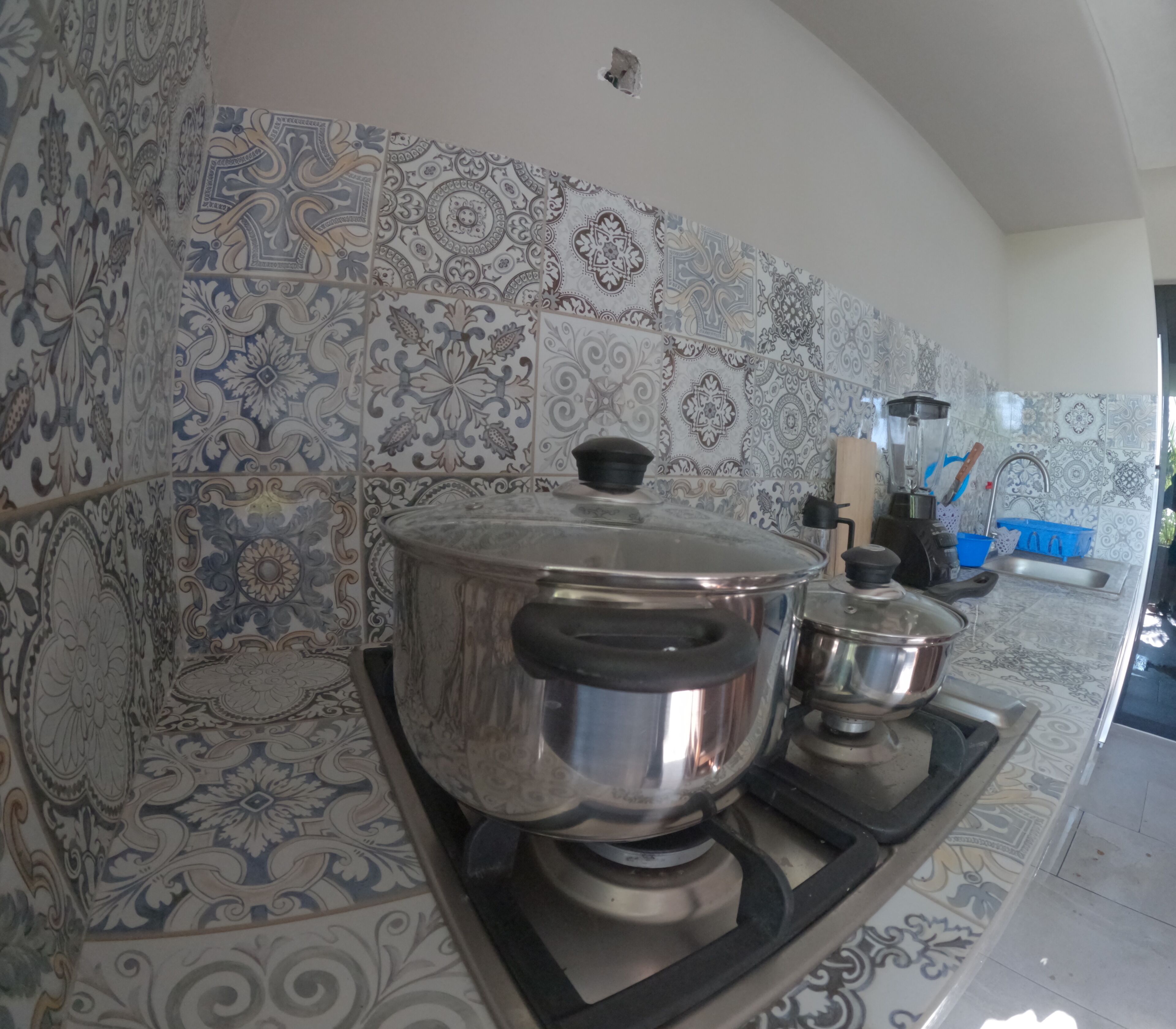 Una cocina con azulejos estampados, una estufa y ollas de cocina.