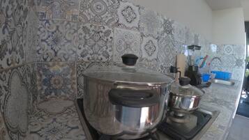 Una cocina con azulejos estampados, una estufa y ollas de cocina.
