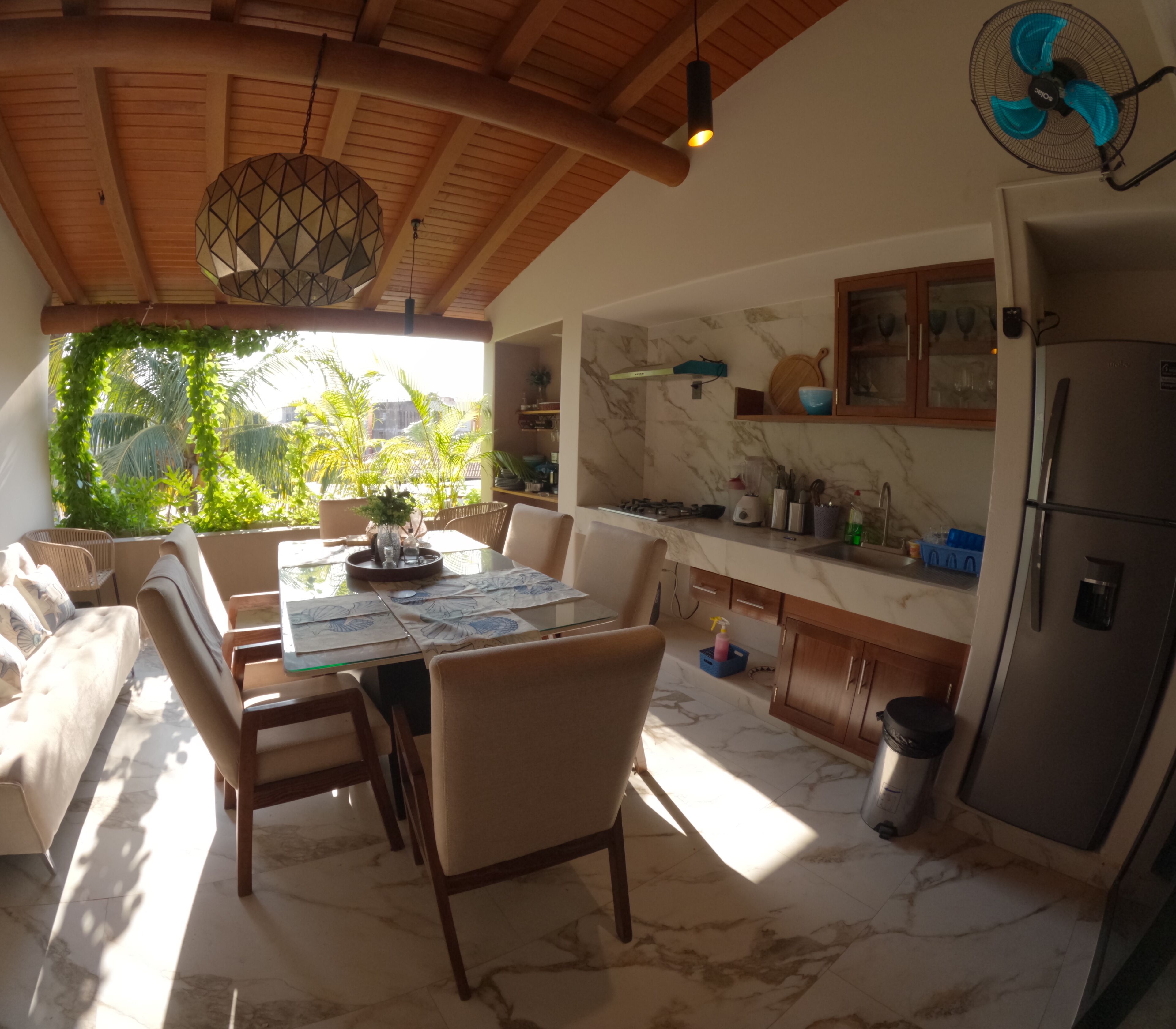 A spacious kitchen with a dining area, marble flooring, and a ceiling fan.