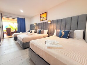 Ein Hotelzimmer mit zwei Betten, einem großen Fenster mit Vorhängen, einem Gemälde an der Wand und einem Balkon mit Tisch und Stühlen.