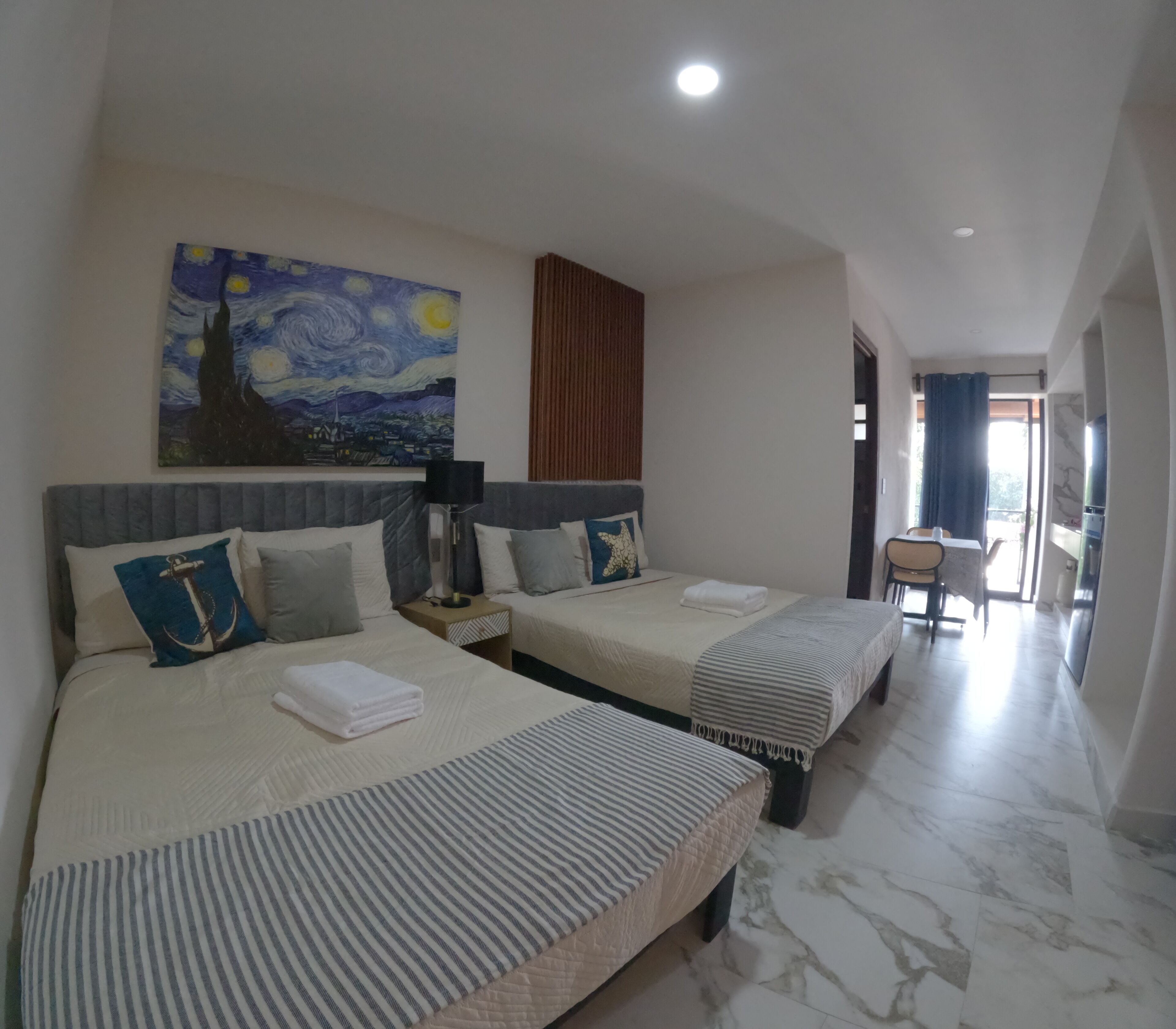 Quarto de hotel com duas camas, um quadro na parede, uma escrivaninha e uma cadeira.
